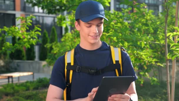 Portrait sorrindo homem correio entrega de alimentos com mochila térmica usa tablet — Vídeo de Stock