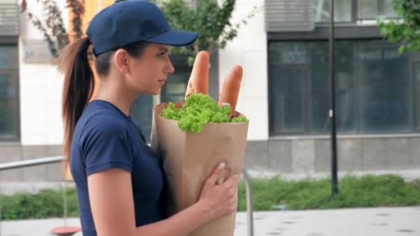 Entrega de comida mensajero mujer con bolsa de papel comestibles para entregar orden cliente — Vídeo de stock