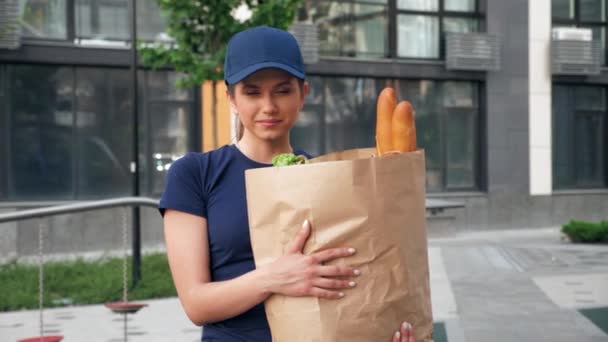 Portret uśmiechnięta kobieta dostawca żywności kurier trzyma torbę papierową z zakupami — Wideo stockowe