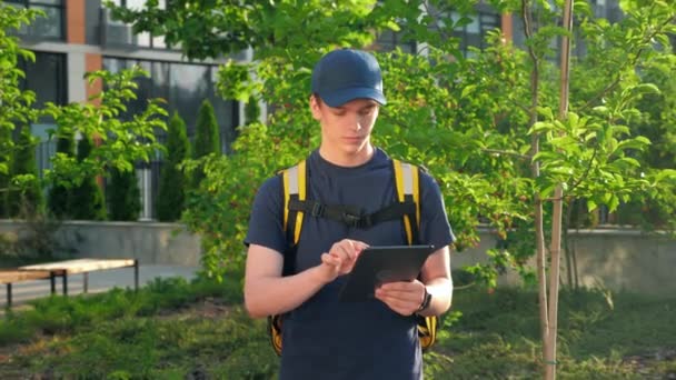 Zoom w poważne dostawy żywności człowiek kurier z plecakiem termicznym wykorzystuje tablet — Wideo stockowe