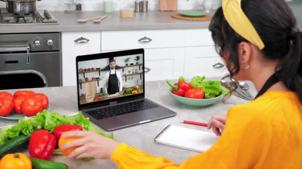 台所の主婦は、シェフがラップトップのウェブカメラで調理のための成分を示しています伝える — ストック動画