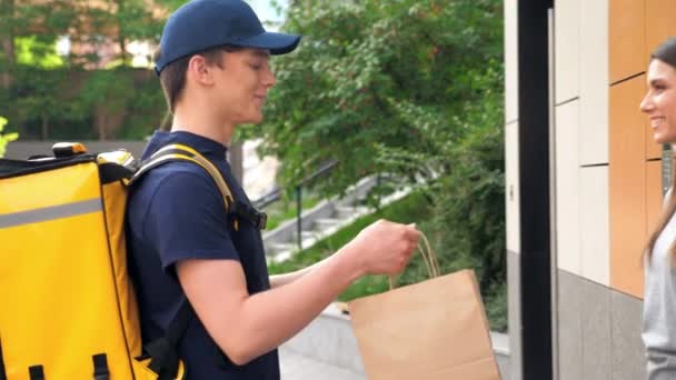 Sorrindo homem de entrega de alimentos mensageiro com mochila térmica entregar mulher ordem — Vídeo de Stock