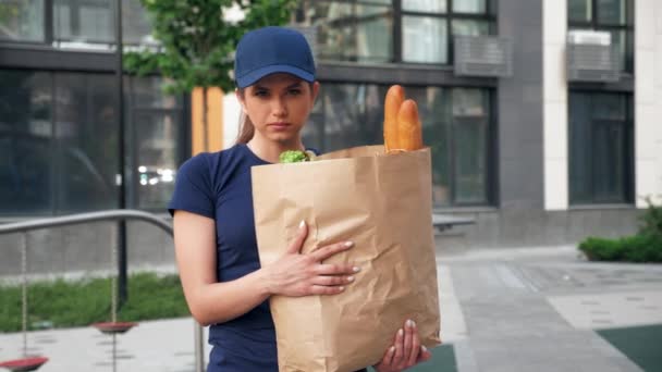 Портрет серьезная доставка пищи женщина курьер держит бумажный пакет с продуктами — стоковое видео
