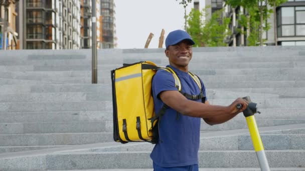 Retrato sorrindo afro-americano homem mensageiro com mochila e scooter elétrico — Vídeo de Stock