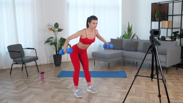 Apto mulher treinador de fitness blogger fazendo exercício dumbbell, treino em casa — Vídeo de Stock