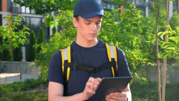 携带热背包的年轻男子快递员使用平板电脑 — 图库视频影像
