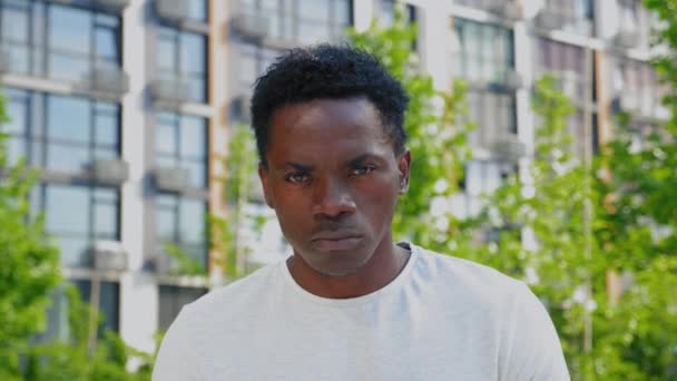 Zblízka vážné afro-americký muž vypadá kamera na pozadí moderní budovy — Stock video
