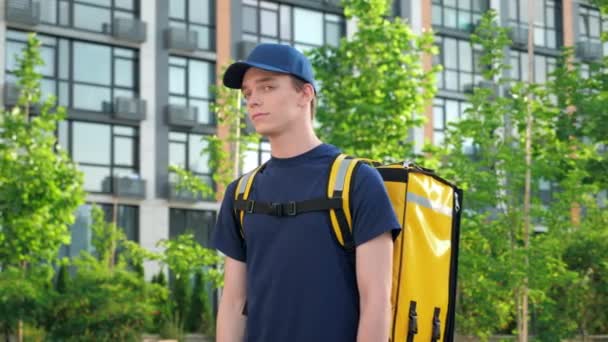 Retrato hombre mensajero entrega de alimentos con mochila térmica gira cabeza mira cámara — Vídeos de Stock