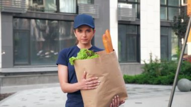 Sipariş müşterisini teslim etmek için kese kağıdı taşıyan kadın kurye.