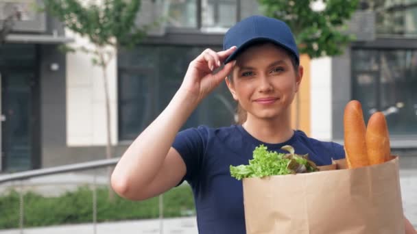 Porträt lächelnde Essenszustellerin hält Papiertüte mit Lebensmitteln in der Hand