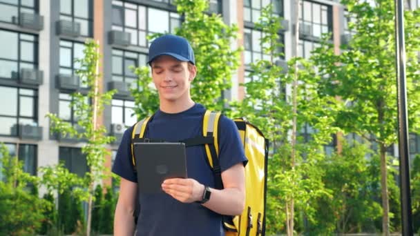 Portrait sorrindo homem correio entrega de alimentos com mochila térmica usa tablet — Vídeo de Stock