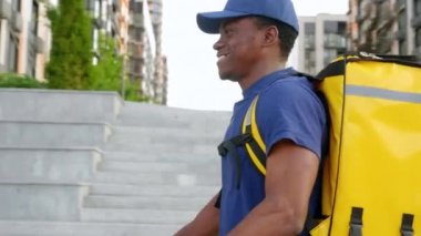 Sırt çantalı Afro-Amerikan kurye teslimatı sokak elektrikli scooter 'ı kullanıyor.