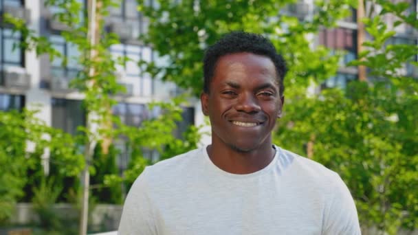 閉じる上の笑顔アフロアメリカ人男性見ますカメラオンバックグランド現代的な建物 — ストック動画