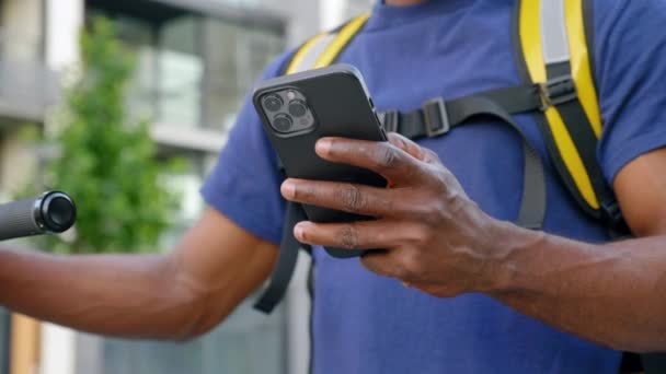 Gros plan homme afro-américain courrier livraison de nourriture utilise smartphone en uniforme bleu — Video