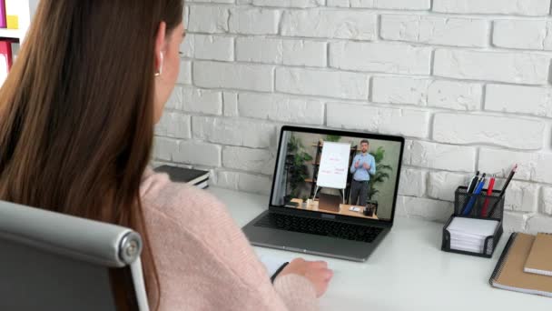 Бізнес-леді в домашньому офісі слухати онлайн відео виклик ноутбук, пише в блокноті — стокове відео