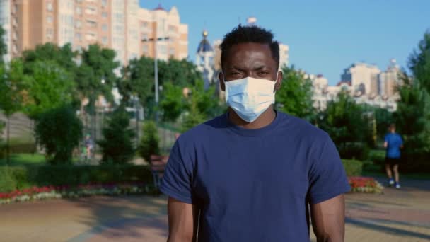 Портрет афро-американца в защитной медицинской маске лица выглядит как камера — стоковое видео