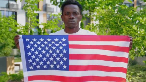 Fényképezőgép zoom afro-amerikai férfi kezében egy amerikai zászló és néz kamera — Stock videók