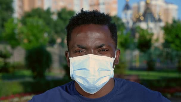 Close up afro-americano uomo adulto in maschera protettiva viso medico guarda fotocamera — Video Stock