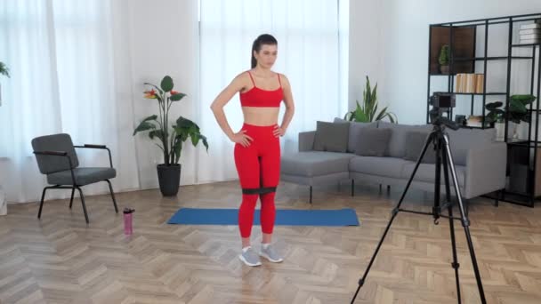 Fit woman fitness blogger tells student doing exercise for legs with loop band — Stok Video