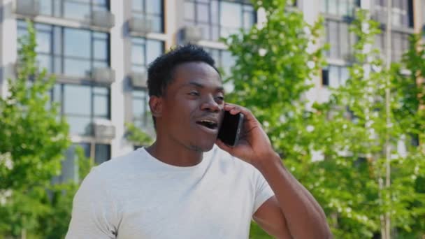 Портрет усміхнений позитивний афроамериканський чоловік розмовляє на мобільному телефоні в парку — стокове відео