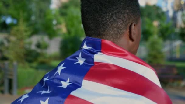 Close-up back view patriot afro-Amerikaanse man loopt straat met USA vlag op rug — Stockvideo