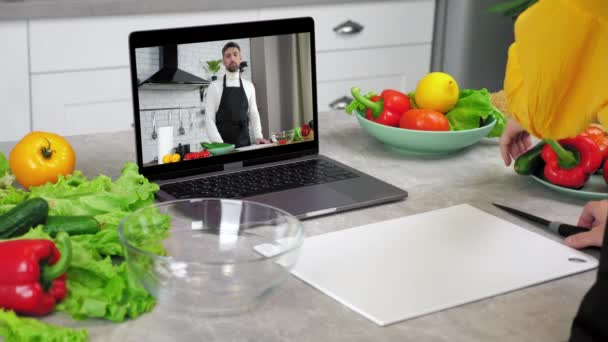 Ama de casa en estudio de cocina video llamada en línea portátil rodajas de tomate escuchar chef — Vídeos de Stock