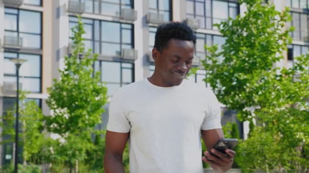 Retrato sorrindo afro-americano homem usa smartphone beber café no verão — Vídeo de Stock