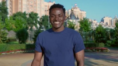 Afro-Amerikalı bir adam çıkar ve yüz maskesini atar, omuzlarında alçı taşır.