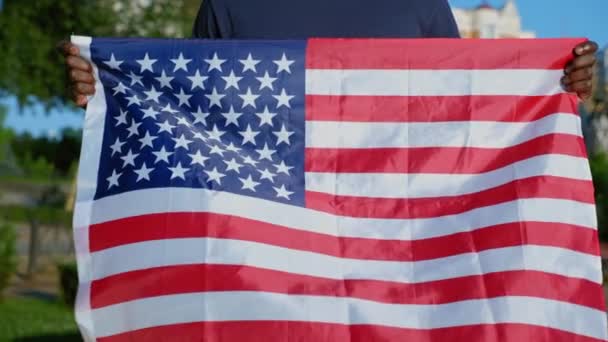 Close up Afro-Amerikaanse man staat in het park met USA vlag in de zomer — Stockvideo