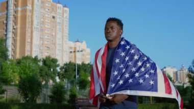 Vatansever Afro-Amerikan adam yazın Amerikan bayrağıyla sokakta yürüyor.