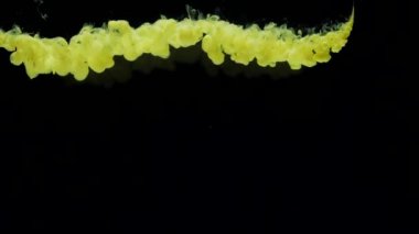 Yavaş çekim sarı mürekkep suya düşer ve karışır, suyun altında yavaşça döner.