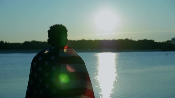 Hombre afroamericano con bandera americana sobre hombros mira a la distancia al amanecer — Vídeos de Stock