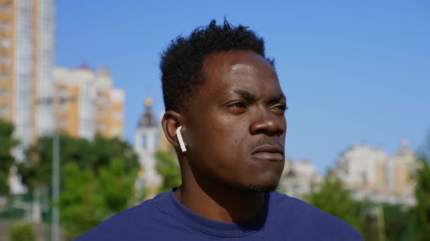 Close-up afro-amerikaanse man freelancer het dragen van draadloze hoofdtelefoon drinkt koffie — Stockvideo