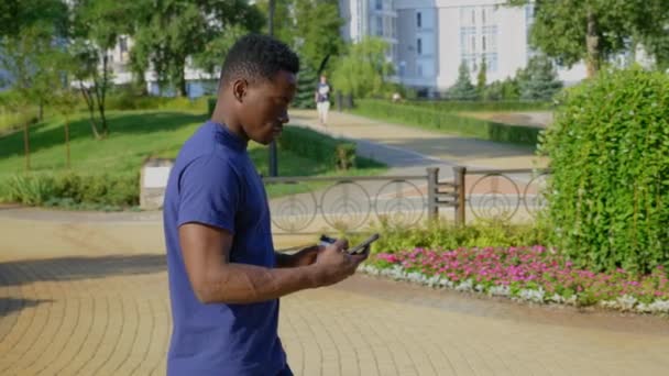 Afro-american man uses mobile phone holding white cup with coffee or tea in hand — Stock Video