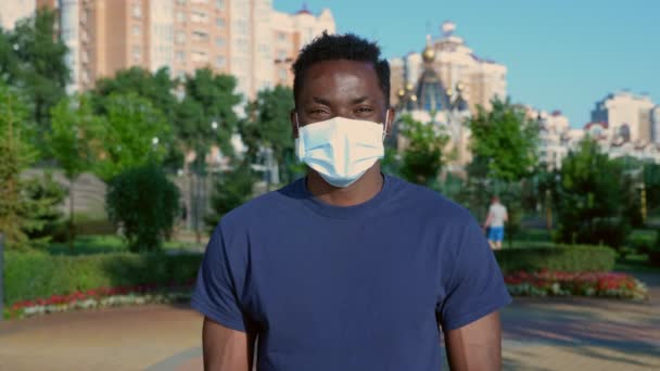 Retrato sonriente hombre afro-americano en máscara protectora de la cara médica se ve cámara — Vídeos de Stock