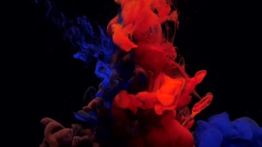 Suyun içinde yavaşça dönen mavi ve kırmızı mürekkep boyaları.
