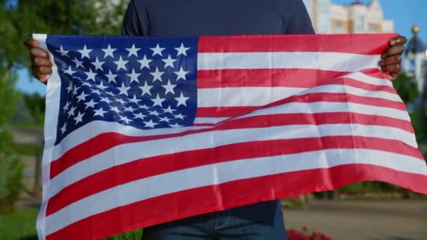 Gros plan Un homme afro-américain se tient dans un parc avec le drapeau des États-Unis en été — Video