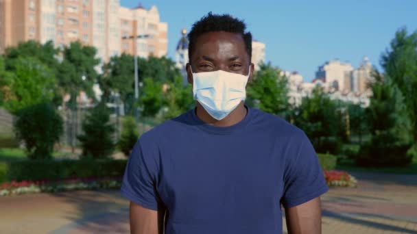 Retrato sorrindo homem afro-americano em proteção máscara facial médica olha câmera — Vídeo de Stock