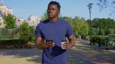 Düşünceli Afrikalı Amerikalı adam sokakta yürüyor. Etrafa bakıyor, akıllı telefon navigatörü.