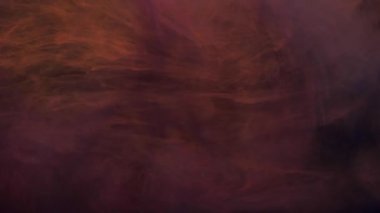 Yavaş hareket eden turuncu ve pembe mürekkep suda karışıyor, yavaşça suyun altında dönüyor.