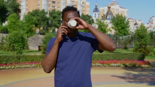 Portret Afro-Amerikaanse man in gesprek op mobiele telefoon het drinken van koffie thee in de zomer — Stockvideo