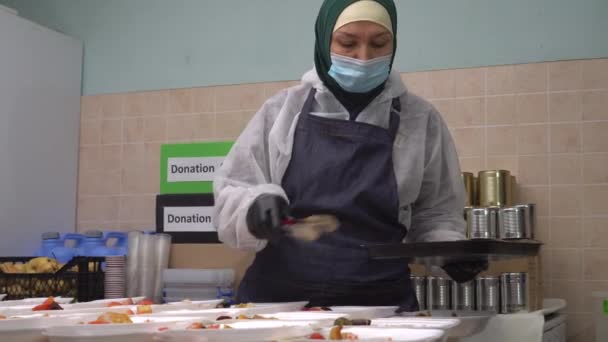 Mulher muçulmana cozinha voluntária no hijab. Caixas de almoço com refeições quentes. Comida para os pobres, alimentar os famintos, dar, doar, organização da caridade. Doação de alimentos durante o Ramadã — Vídeo de Stock