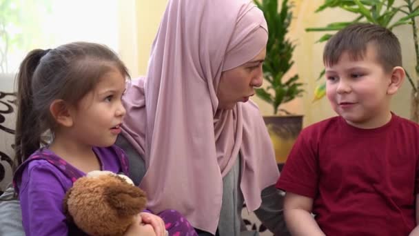 Tecrit sırasında Müslüman anne ve çocuklar evde birlikteler. Küçük bir kız ve oğluyla oynayan mutlu bir kadın. — Stok video