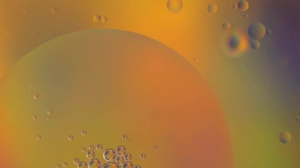 Macro oil drop in water. Yellow, green, orange bubbles background — Video