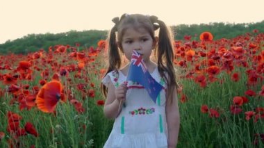 Yeni Zelanda bayrağı taşıyan küçük güzel bir kız bebek. Kırmızı gelincik, Anzak Günü. Gelincik tarlası