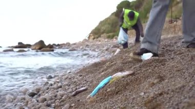 Deniz balığı yüz maskelerinin kulaklarına dolanır ve ölür. Okyanus sahilinde atılmış maske ve eldivenler. PPE 'nin yanlışlıkla imha edilmesi deniz yaşamını öldürüyor. Gönüllüler sahilde çöp topluyor.