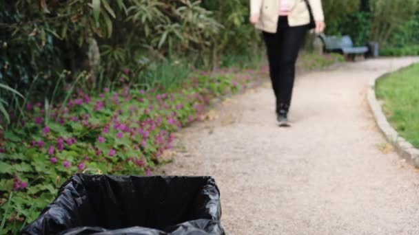 Coronavirus medisch afval. Een vrouw gooit een gebruikte wegwerpmasker in een vuilnisbak in het stadspark. Covid-19 pandemie en milieuvervuiling — Stockvideo