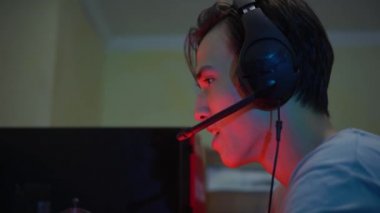 Genç profesyonel oyuncu bilgisayarında online video oyunları oynuyor. Maçı kazandığı için gülümsüyor, takipçileri ve aboneleri için canlı yayın yapıyor. Sanal spor konsepti. Takım oyunu