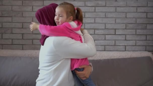 Buona madre musulmana e figlioletta. Amare la madre in hijab abbraccia e bacia la sua figlia sorridente. Eid, Ramadan, buona festa della mamma. Godersi il tempo insieme a casa — Video Stock