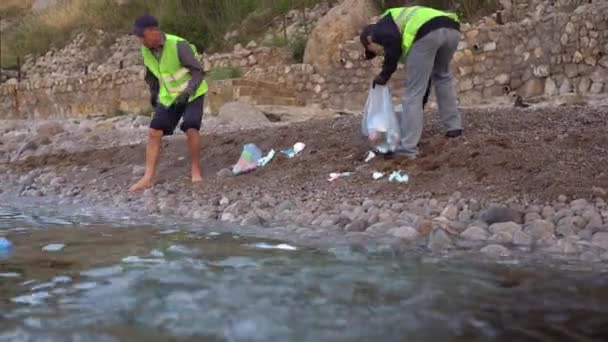 Plásticos de uso único para combater o coronavírus estão poluindo o meio ambiente. Voluntários e limpadores limpam o litoral de máscaras médicas e lixo — Vídeo de Stock